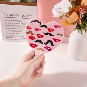 Pink heart-shaped handheld makeup mirror with lip and mustache patterns on the back