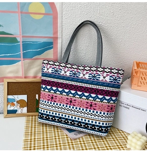 Detailed view of bohemian woven tote bag with colorful geometric patterns on a plaid cloth