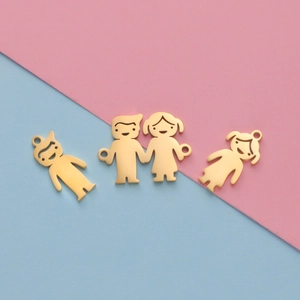Close-up of golden boy and girl shaped charms on a pink and blue background