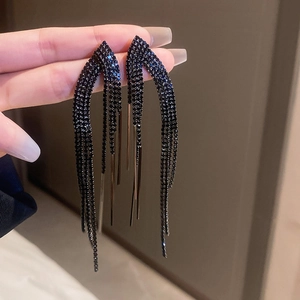 Detailed view of long black tassel earrings with crystal fringe held by hand