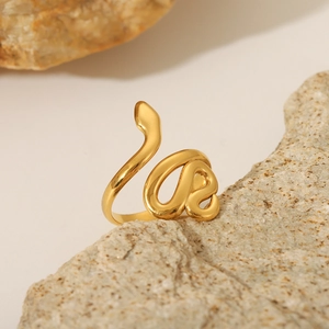 Bague élégante en acier inoxydable doré en forme de serpent sur texture de pierre