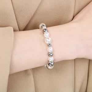 Gros plan d'un élégant bracelet de perles d'eau douce blanches et perles argentées au poignet