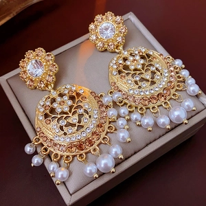Macro shot of vintage gold hollow earrings with sparkly rhinestones and white pearl tassels