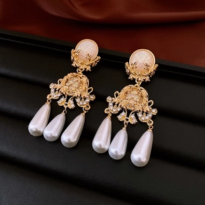 Macro detail of vintage baroque earrings with gold metal carving and pearl drops