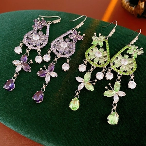 Detail of drop earrings with zircon flowers and tassels in purple and green