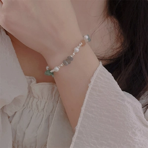 Detail of beaded bracelet with white pearls, green raw stones and silver spacer beads