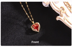 Macro detail of a gold heart pendant featuring a large red faceted crystal and white zircons