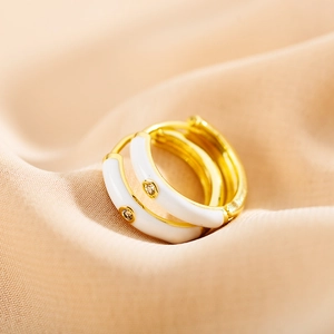 Macro view of gold-plated hoop earrings with white enamel and sparkling zircon stone