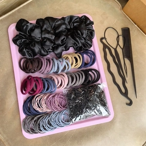 Comprehensive hair styling set with scrunchies and colorful elastic bands in a pink tray