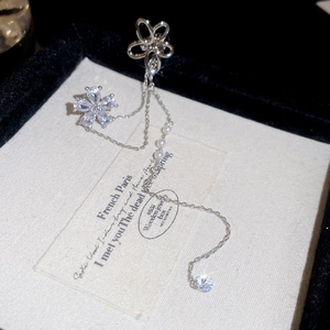Détail de l'oreille à pompon argenté avec motifs de fleurs en zircon et perles