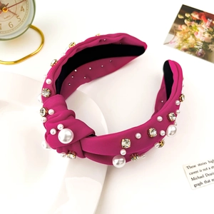 Detail of rose red knotted headband featuring inlaid faux pearls and shiny rhinestones