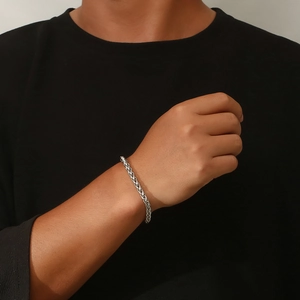 Bracelet classique en acier titane argenté pour homme porté au poignet sur un fond sombre