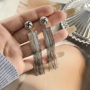 Detail of silver long tassel earrings held in hand showcasing sleek metallic texture