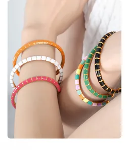Close-up of colorful enamel tile bracelets stacked on wrist for a modern layered look