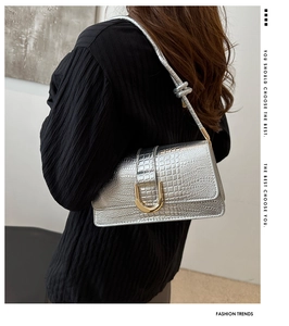 Détail du sac à bandoulière argenté à motif crocodile avec boucle et bandoulière nouée