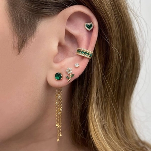 Macro detail of gold flower tassel earrings with green zircons on a female model