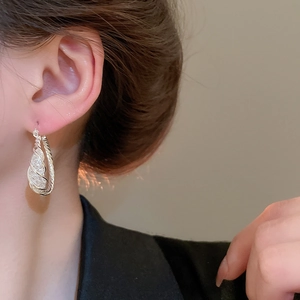 Close-up of silver mesh circular hoop earring on model showing glittering texture