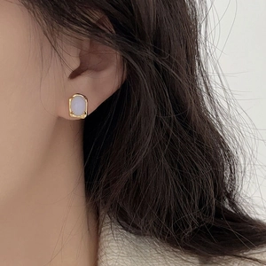 Close-up of a 925 sterling silver irregular gold earring with a light blue gemstone