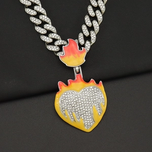 Macro view of iced out Cuban chain with yellow and red enamel flame heart pendant