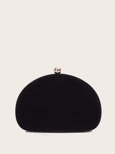 Detailed close-up of a black velvet shell clutch bag with a polished gold spherical clasp