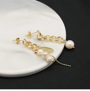 Macro detail of natural pearl tassel earring on a marble tray with handmade engraving