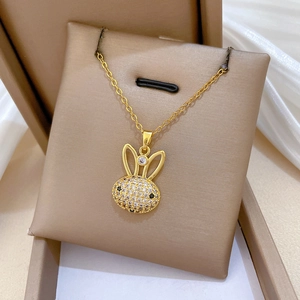 Gros plan du pendentif lapin doré serti de cristaux dans un coffret à bijoux beige