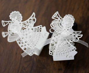 Macro view of white laser-cut angel gift box with hollow patterns and white ribbon