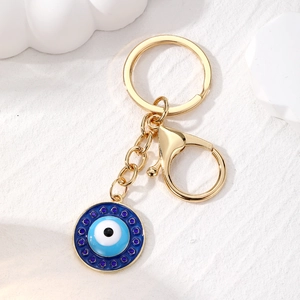 Macro detail of gold-plated evil eye keychain featuring blue resin and crystal inlay