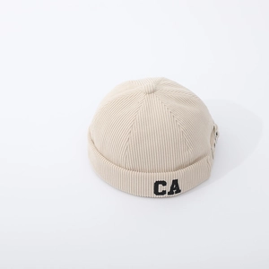 Detail of beige ribbed knit baby cap with black CA embroidery and adjustable strap