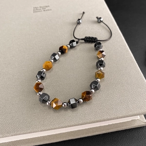 Detail of adjustable tiger eye and hematite beaded bracelet with braided cord on a notebook