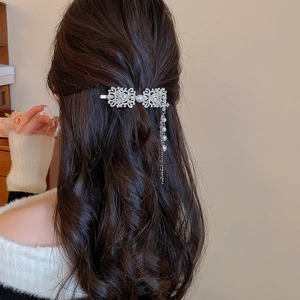 Detail of silver tassel hair clip with rhinestones and pearls on wavy brown hair