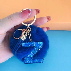 Detail view of blue faux fur pompom keychain with glitter letter Z and golden hardware
