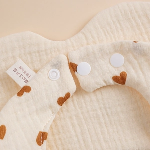 Soft cotton gauze baby bib with brown heart patterns and secure snap closure