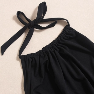 Close-up of black halter dress featuring a bow tie neckline and elastic pleated details
