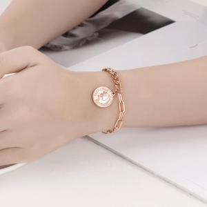 Détail du bracelet à boucle OT en or rose avec pendentif pièce Élisabeth II gravé
