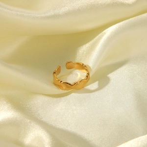 Detail of gold hammered wavy open ring on elegant cream satin fabric background