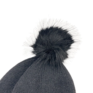 Close-up of the fluffy faux fur pompom and fine knit texture on a black winter beanie