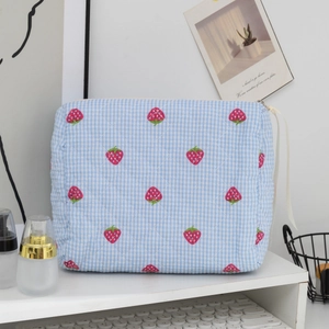 Détail de la trousse de maquillage matelassée à carreaux bleus avec fraises et ruban de zip