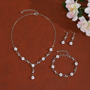 French rose jewelry set with white flowers and crystals on a brown textured background