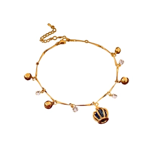 Bracelet vintage doré avec pendentif couronne, clochettes et cristal bleu sur fond blanc