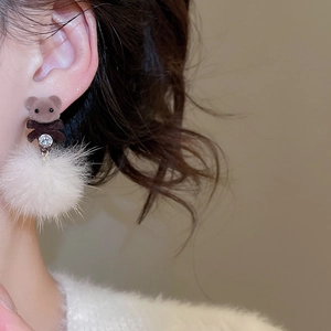 Close-up of brown flocked bear earring with white pompom and sparkling crystal accent