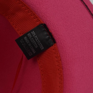 Detail view of the rose red felt fedora hat interior showing the 65% cotton blend label