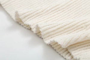Primer plano de la suave textura de punto acanalado blanco del vestido de manga larga
