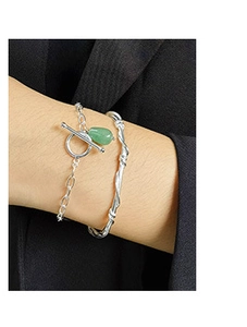 Detailed shot of silver twisted bangle and chain bracelet with green teardrop pendant
