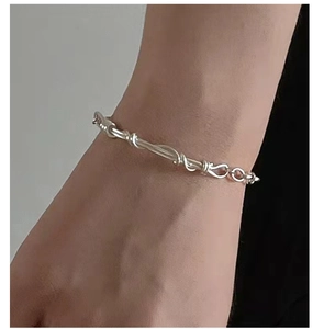 Macro detail of the woven silver minimalist hand-twisted rope bracelet on a wrist