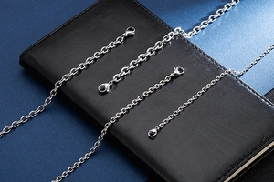 Detailed macro view of silver stainless steel rollo chains with lobster clasps on leather
