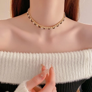 Close-up of golden necklace with sparkling square and round crystals on a model's neck