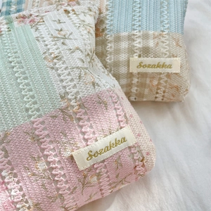 Detailed macro view of fresh floral lace quilting and branded woven label on makeup bag