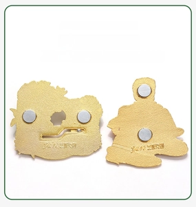 Detail view of the strong magnetic backing on two golden metal souvenir fridge magnets