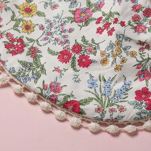 Gros plan du bavoir fleuri avec bordure délicate en dentelle à pompons au crochet crème